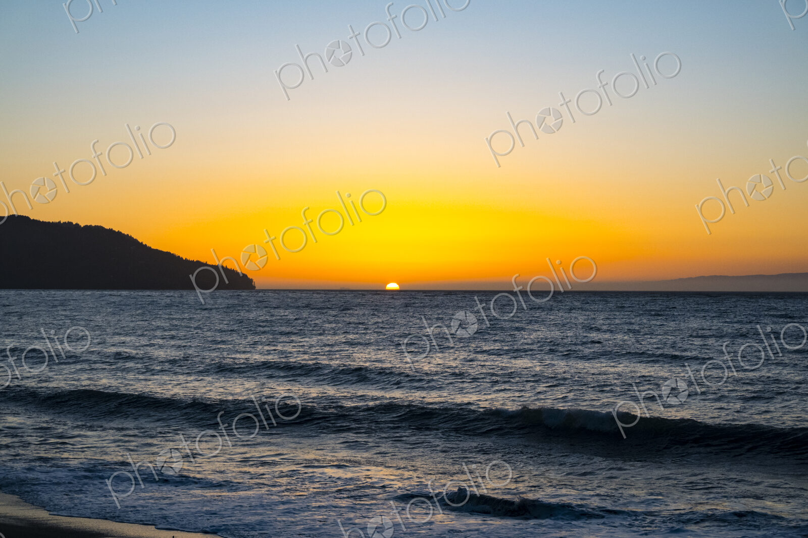Sun setting on the horizon above the Strait of Juan de Fuca over the sea.