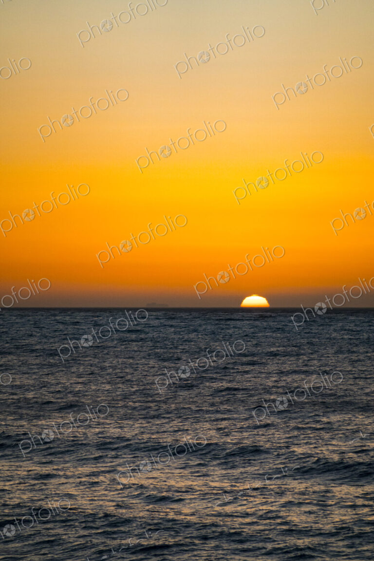 Sun setting on the horizon above the Strait of Juan de Fuca over the sea.