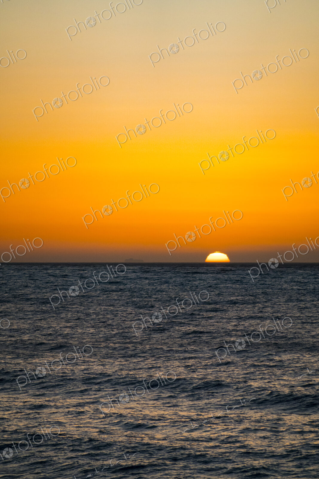 Sun setting on the horizon above the Strait of Juan de Fuca over the sea.