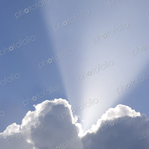 Sun shining behind cumulonimbus clouds in a blue sky. Sun shining behind cumulonimbus clouds in a blue sky.