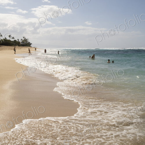 Sunbathers on Waimea Bay Beach on shore and in the water. Sunbathers on Waimea Bay Beach on shore and in the water.