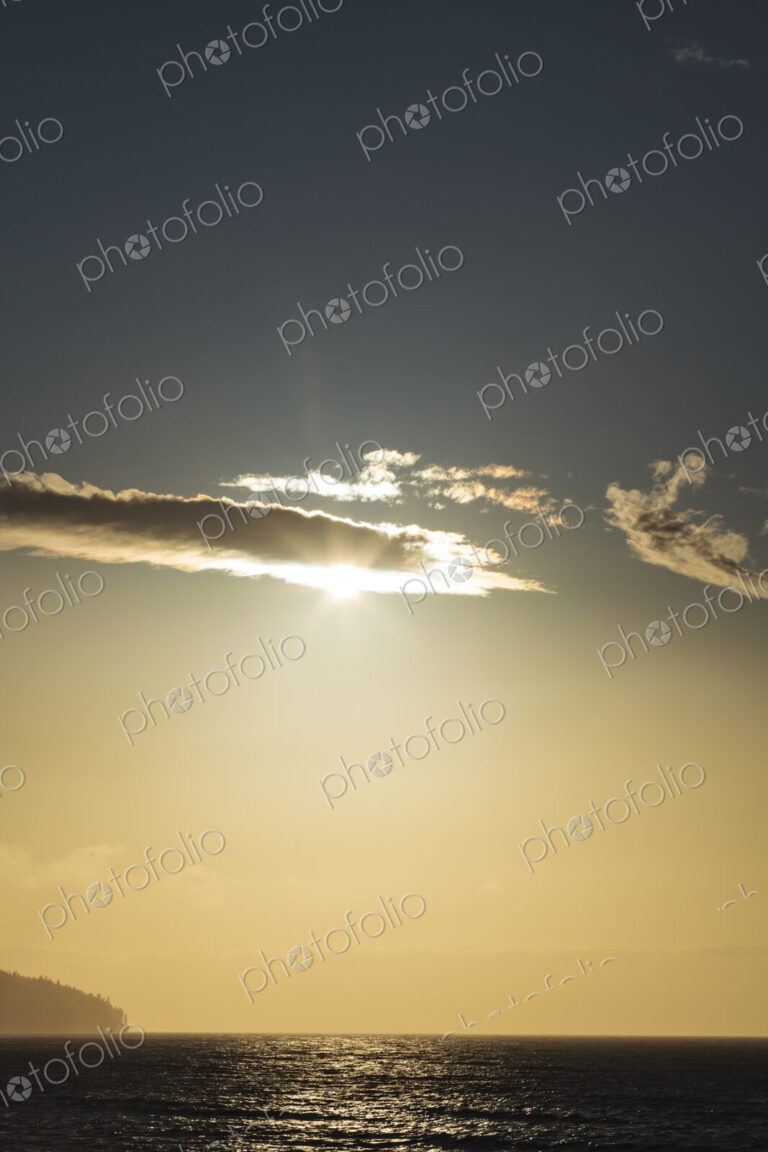 Sunlight over the Strait of Juan de Fuca, lighting up the clouds passing across the sun.