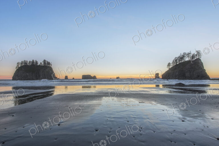 Sunrise horizon behind rock formations on beach