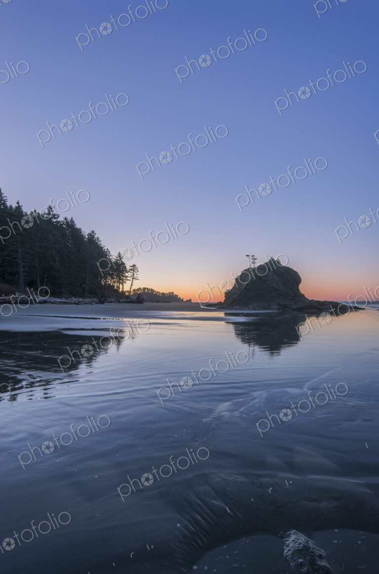 Sunrise horizon behind rock formations on beach