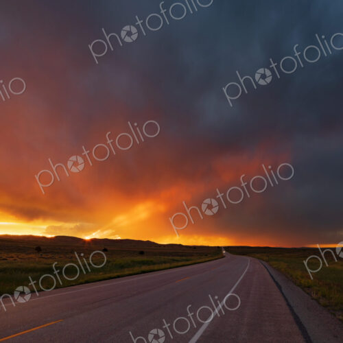 Sunset on WY Highway 59, the glow of the setting sun on the horizon, and storm clouds…