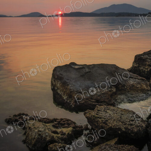 Sunset over a flat calm sea and view of land masses on the horizon. Sunset over a flat calm sea and view of land masses on the horizon.
