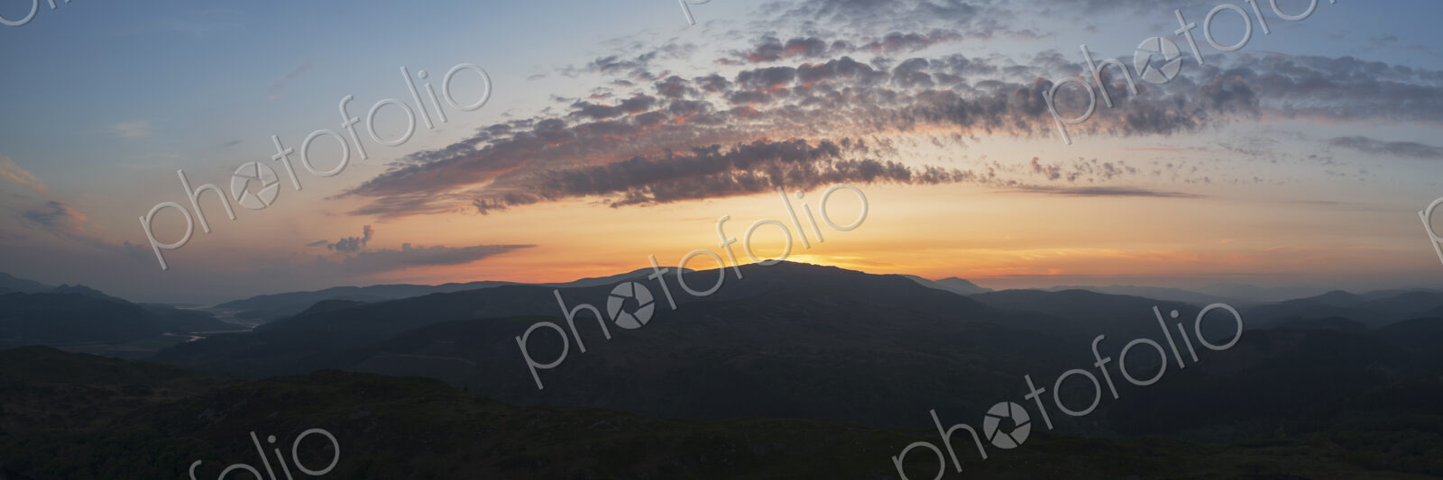 Sunset over the Mawddach Estuary, silhouettes of the hills, and view to the sea.