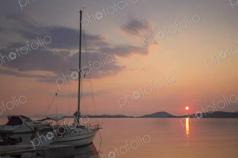Sunset over the Mediterranean Sea. A yacht moored at a jetty.