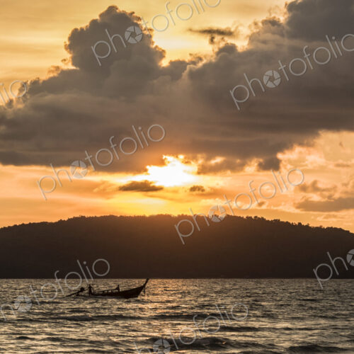 Sunset over wooded land with ocean in foreground. Sunset over wooded land with ocean in foreground.
