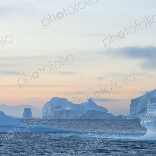Sunset sky and floating icebergs with smooth eroded shapes on the waters of… Sunset sky and floating icebergs with smooth eroded shapes on the waters of…