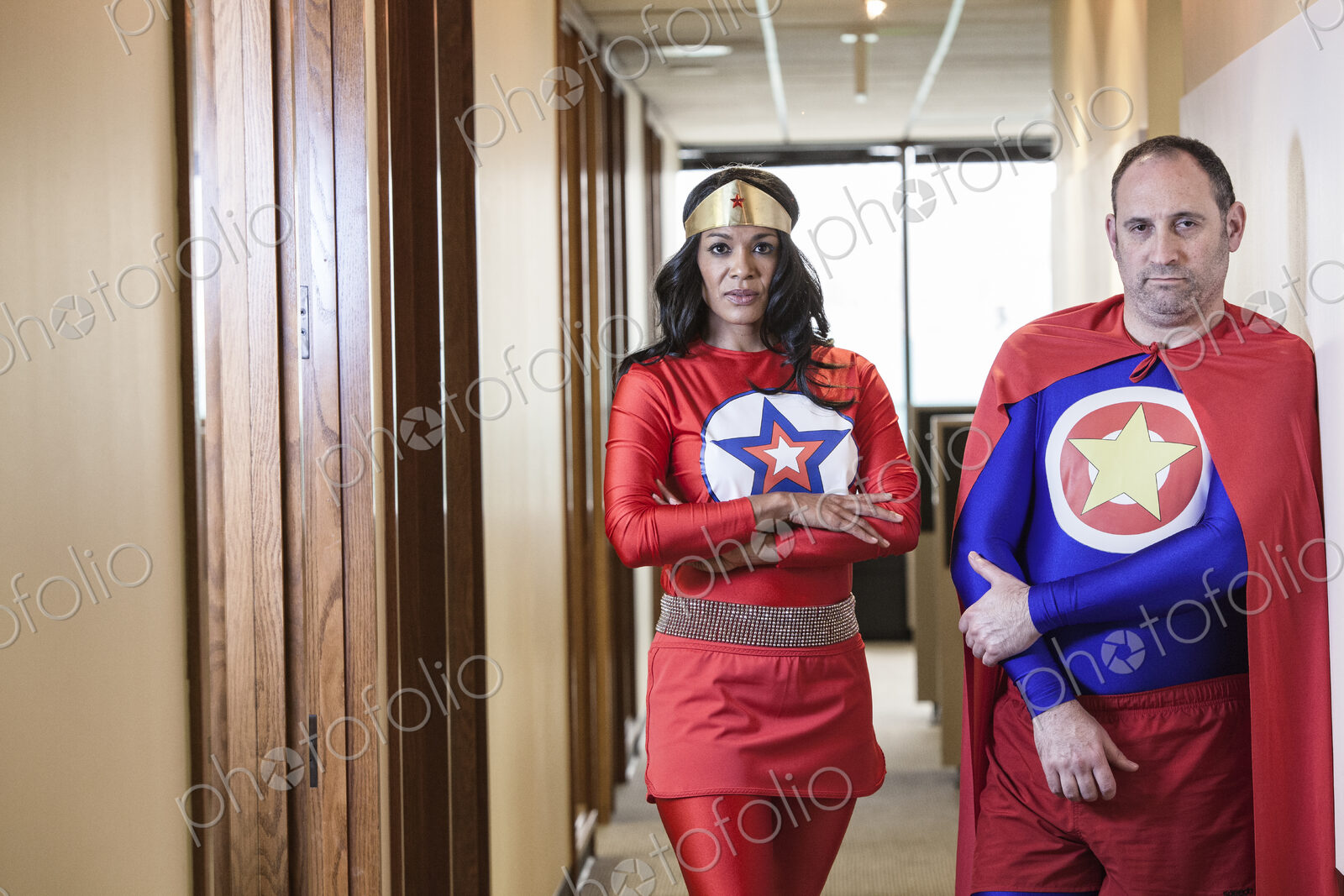 Super hero office team made up of a black woman and a middle aged caucasian man.