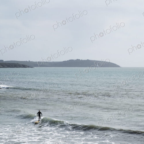 Surfer wearing wet suit riding ocean wave close to shore. need model release form! Surfer wearing wet suit riding ocean wave close to shore. need model release form!