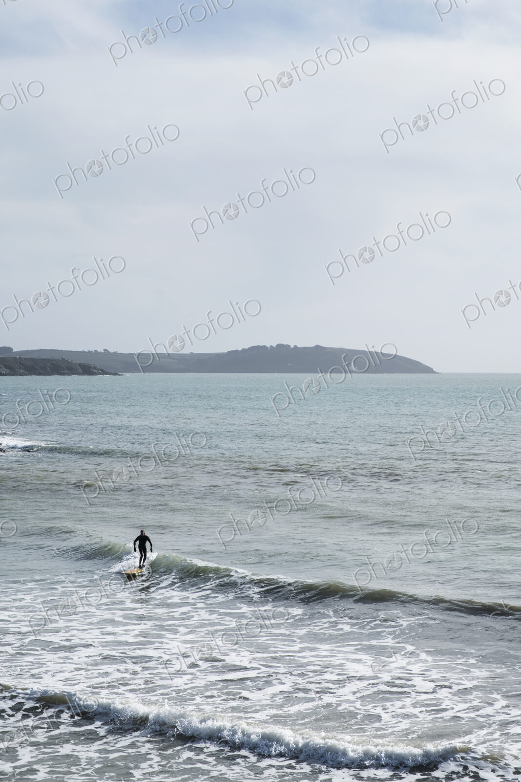 Surfer wearing wet suit riding ocean wave close to shore. need model release form!