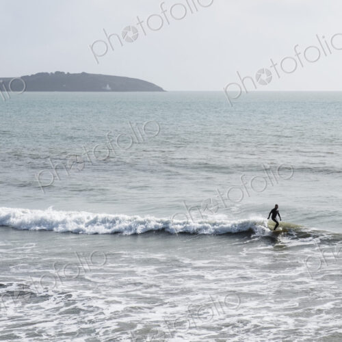 Surfer wearing wet suit riding ocean wave close to shore. need model release form! Surfer wearing wet suit riding ocean wave close to shore. need model release form!