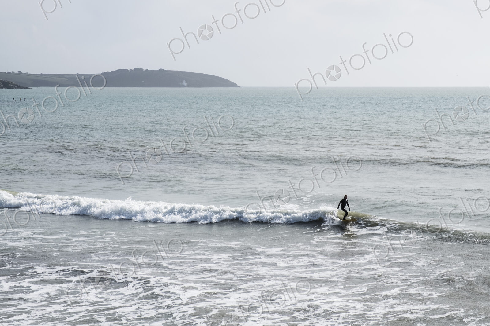 Surfer wearing wet suit riding ocean wave close to shore. need model release form!