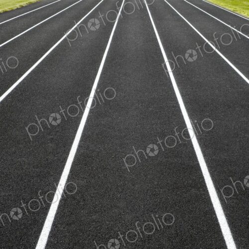 Symmetrical view of white-lined running lanes on a black asphalt track - a clean,…