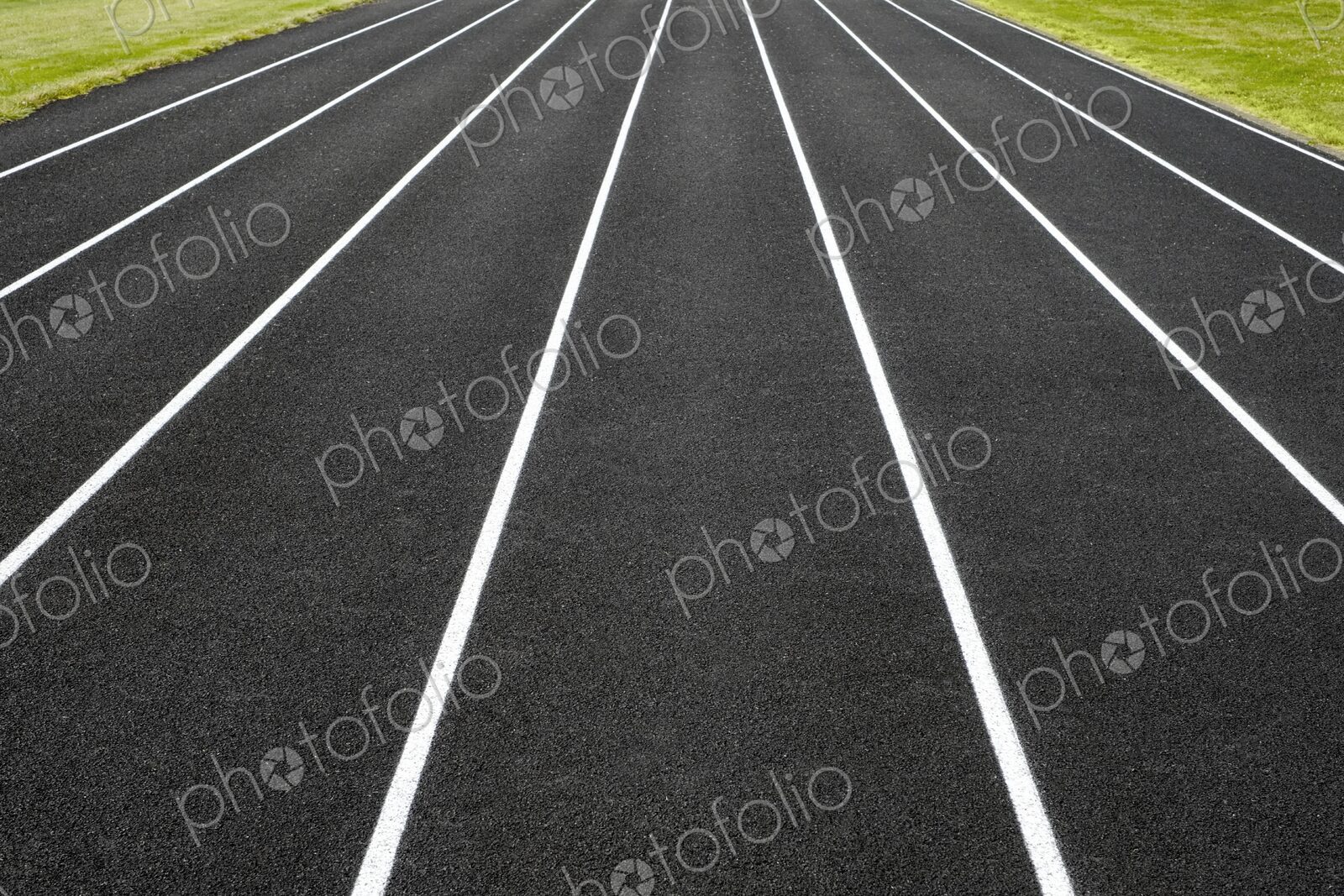 Symmetrical view of white-lined running lanes on a black asphalt track – a clean,…