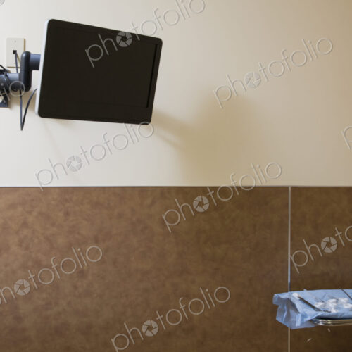 TV screen on wall of hospital with tray of surgical instruments on table. TV screen on wall of hospital with tray of surgical instruments on table.
