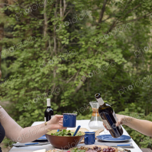 Table in a garden set with plates and food, a man pouring a glass of wine. Table in a garden set with plates and food, a man pouring a glass of wine.