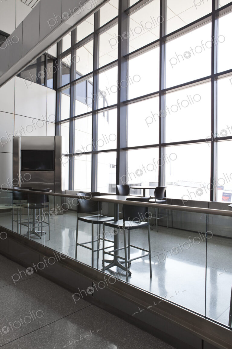 Tables and chairs at a cafe in an airport departure area.