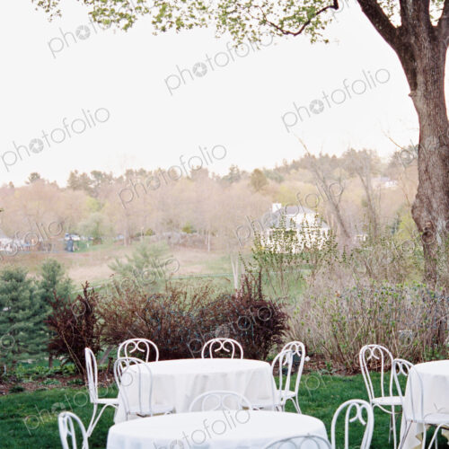 Tables and chairs set with white table clothes in a hotel garden overlooking a wooded… Tables and chairs set with white table clothes in a hotel garden overlooking a wooded…