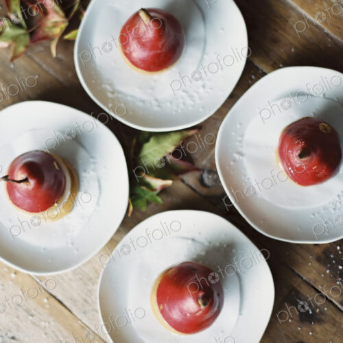 Tabletop viewed from above. Four plates with dessert. Pears dipped in sauce. Tabletop viewed from above. Four plates with dessert. Pears dipped in sauce.