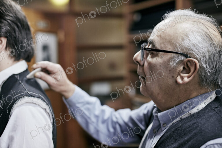 Tailor fitting a jacket on a customer using tailor's chalk to mark the fabric.