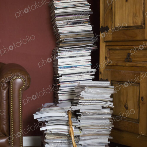 Tall stack of magazines in a basket leaning against a wall. Tall stack of magazines in a basket leaning against a wall.