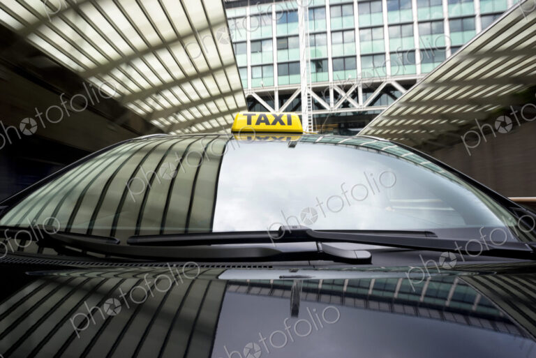 Taxi cab emerging from a garage underneath an office building.
