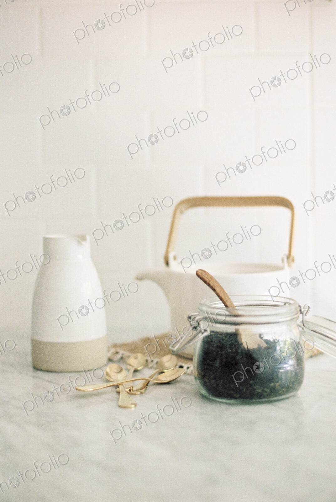 Tea pot, jug and a glass jar with black tea leaves.