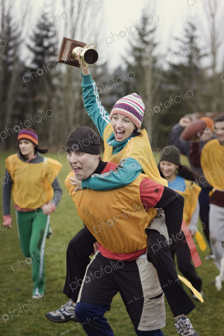 Team members celebrating a victory and a trophy in an outdoor sporting event in the…