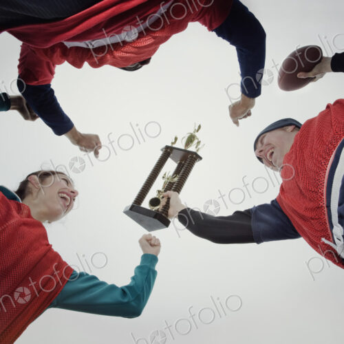 Team members celebrating a victory and a trophy in an outdoor sporting event in the…