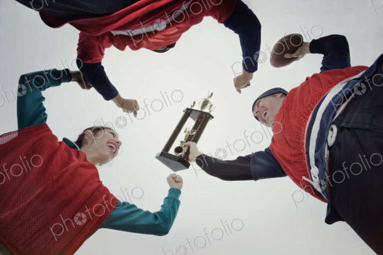 Team members celebrating a victory and a trophy in an outdoor sporting event in the…