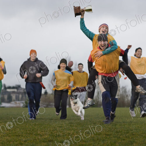 Team members celebrating a victory and a trophy in an outdoor sporting event in the… Team members celebrating a victory and a trophy in an outdoor sporting event in the…