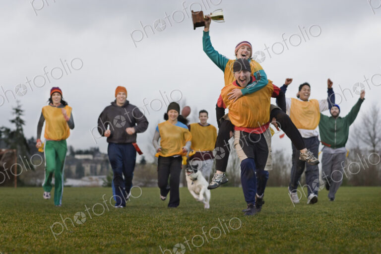 Team members celebrating a victory and a trophy in an outdoor sporting event in the…