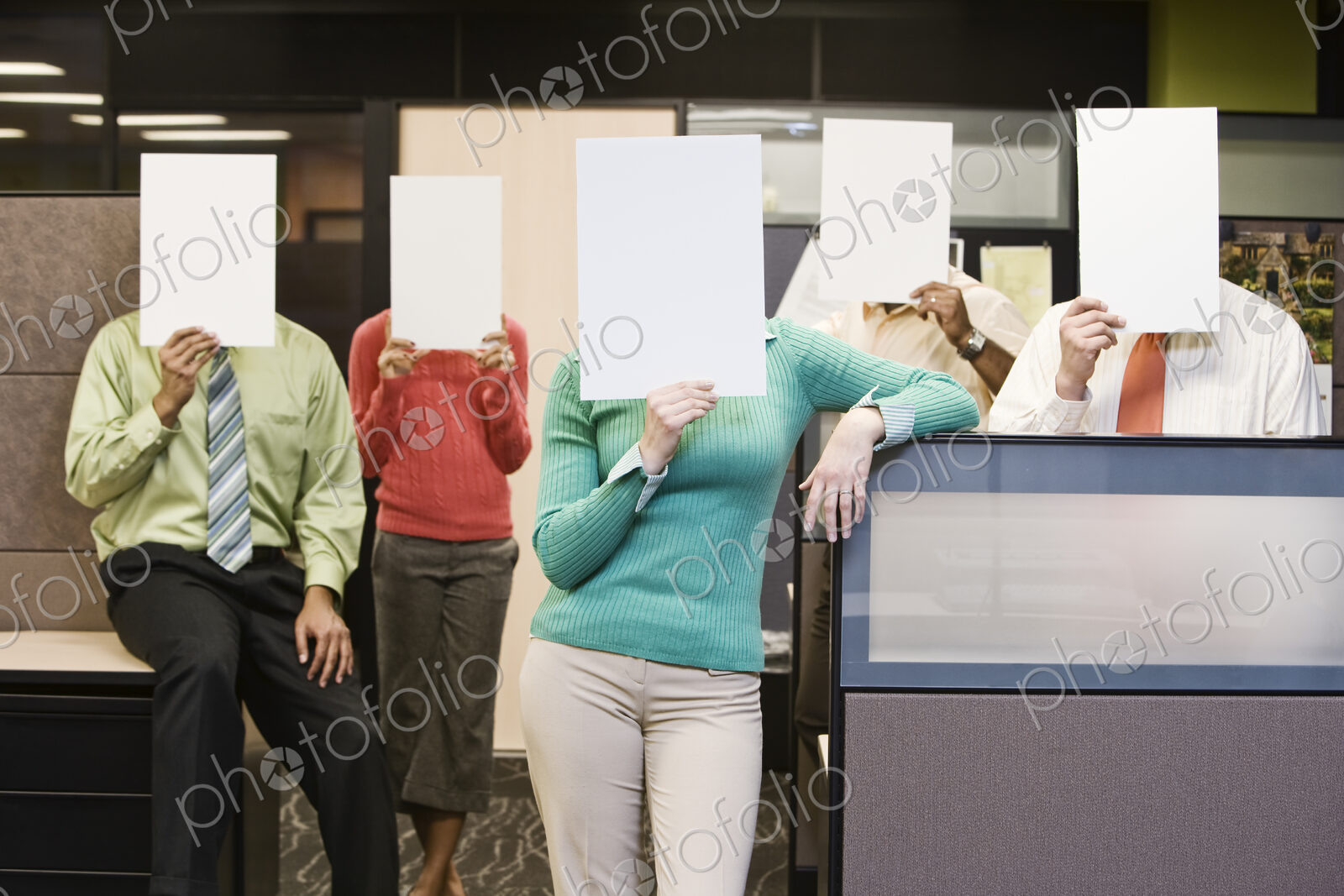 Team of business people standing with blank pieces of paper in front of their faces.