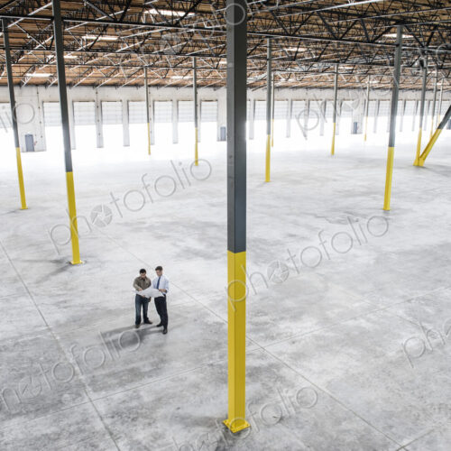 Team of people checking out the new interior of an empty warehouse space. Team of people checking out the new interior of an empty warehouse space.