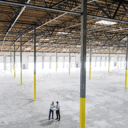 Team of people checking out the new interior of an empty warehouse space. Team of people checking out the new interior of an empty warehouse space.