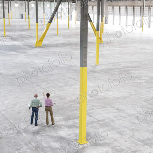 Team of people checking out the new interior of an empty warehouse space. Team of people checking out the new interior of an empty warehouse space.