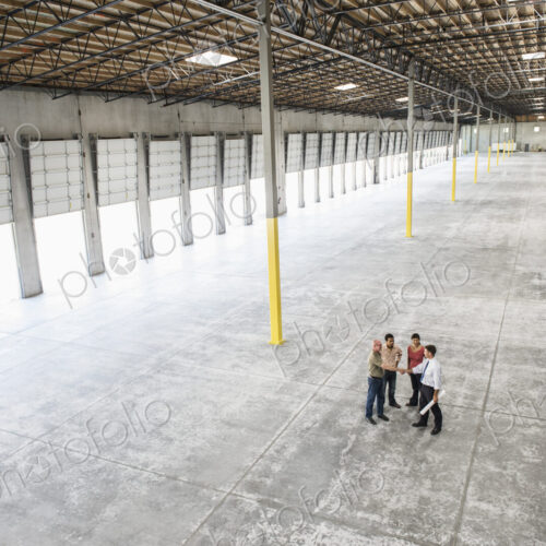 Team of people checking out the new interior of an empty warehouse space. Team of people checking out the new interior of an empty warehouse space.
