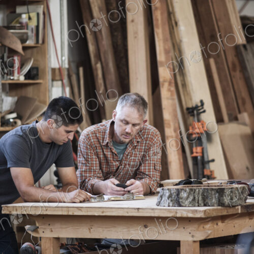 Team of two caucasian men factory workers problem solving at a work station in a…