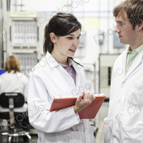 Team of two male and female techinicians in white coats in a research development role Team of two male and female techinicians in white coats in a research development role