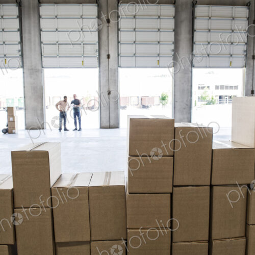Team of workers check out inventory in front of loading dock doors in a new warehouse. Team of workers check out inventory in front of loading dock doors in a new warehouse.