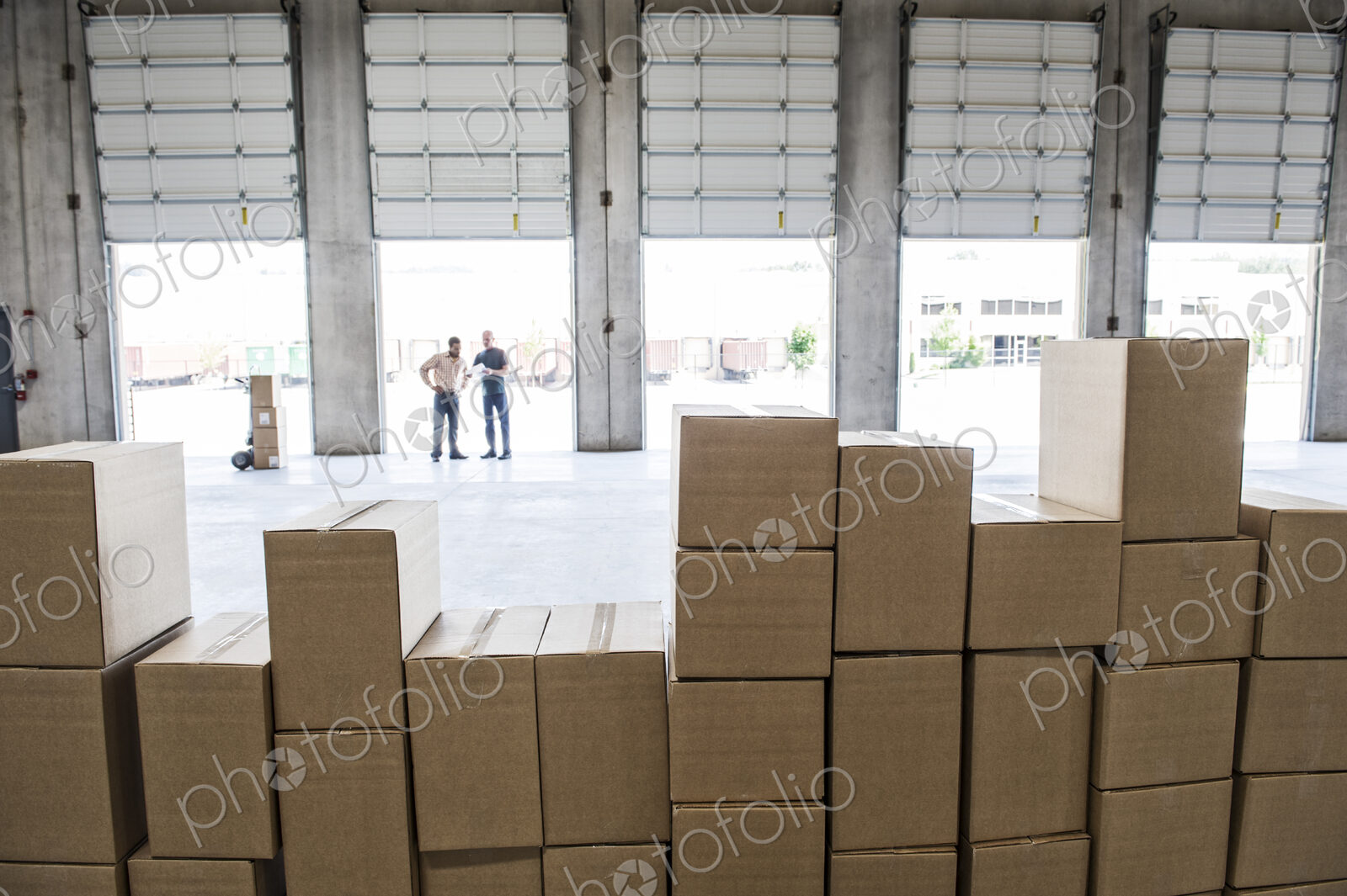 Team of workers check out inventory in front of loading dock doors in a new warehouse.