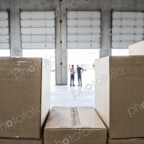 Team of workers check out inventory in front of loading dock doors in a new warehouse. Team of workers check out inventory in front of loading dock doors in a new warehouse.