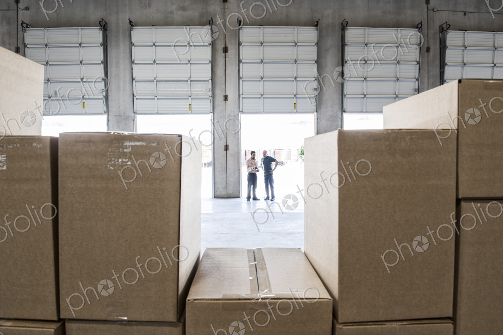 Team of workers check out inventory in front of loading dock doors in a new warehouse.