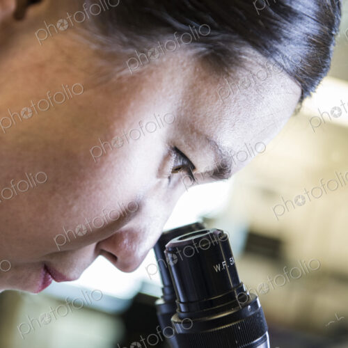 Technician using a microscope to examine an item
