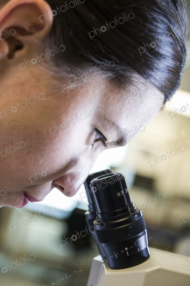 Technician using a microscope to examine an item