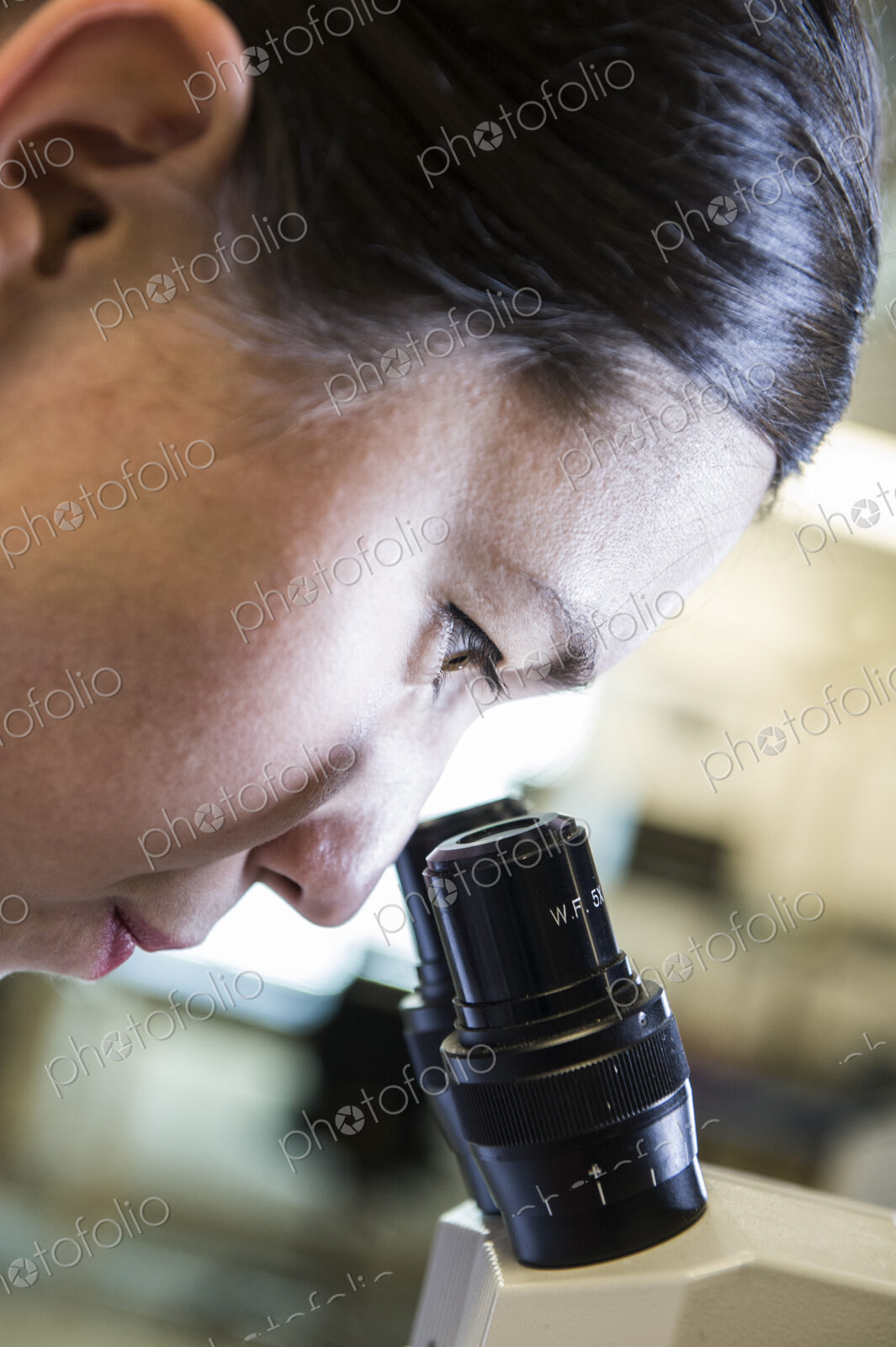 Technician using a microscope to examine an item