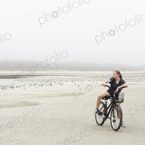 Teen girl biking on sand at the beach, St. Simon's Island Georgia